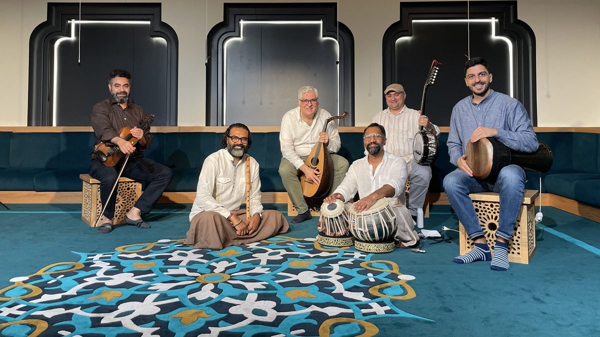 Six musicians in an Arabic majlis-style session: violin, ney, oud, tabla and percussion