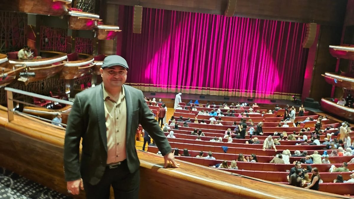 Wael Salah at the balcony of a concert hall before a performance, with a lit magenta curtain