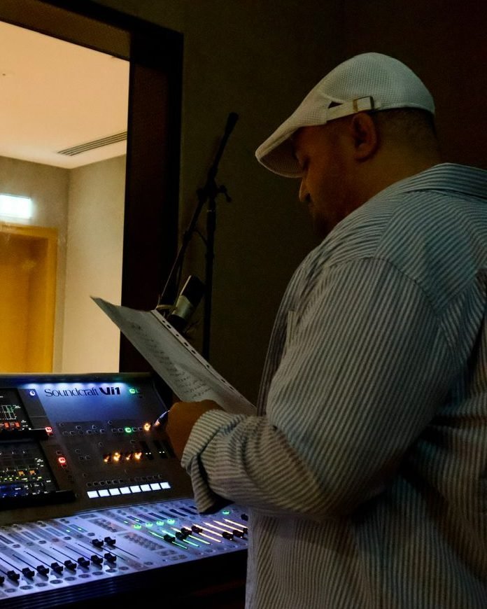 Wael Salah checking the lyric sheet at the mixing desk while directing a studio recording session