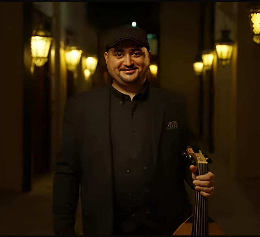 Wael Salah holding his oud in a lantern-lit alley